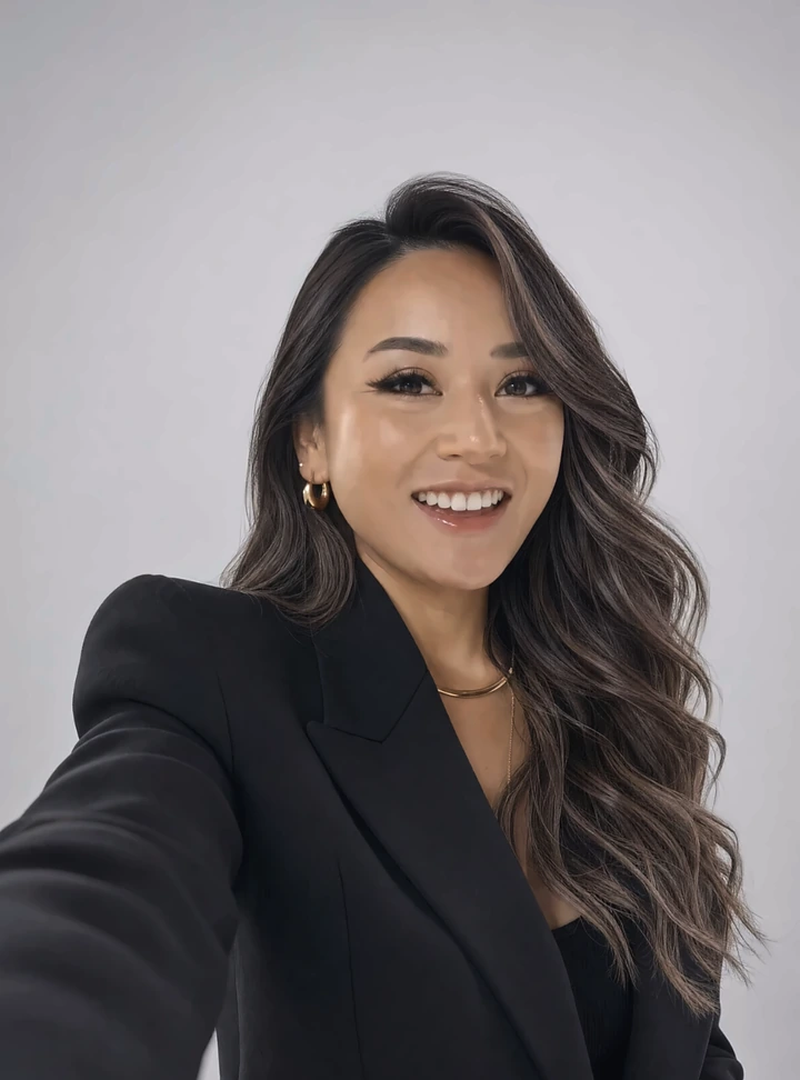 Tawny Noelle in a black blazer, smiling, against a grey studio backdrop